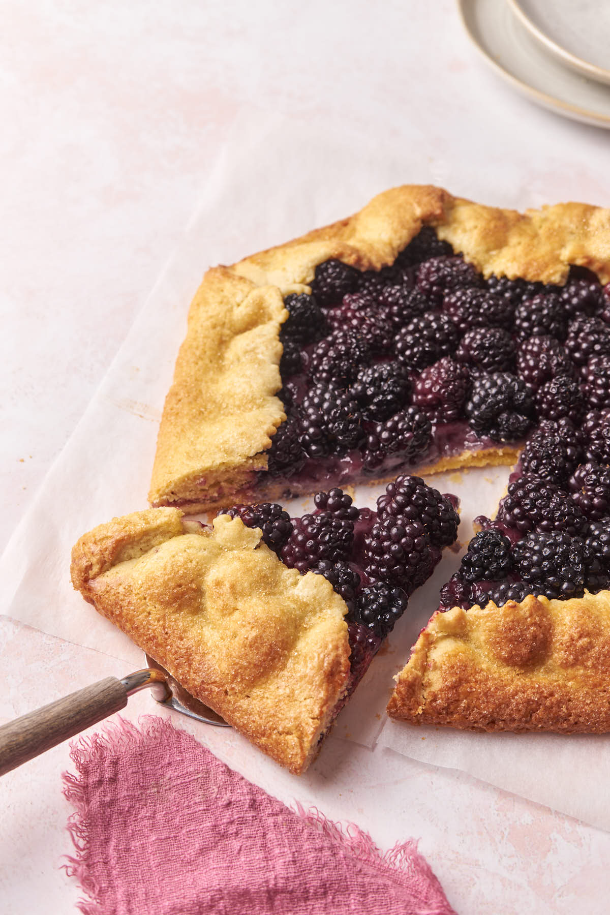 a blackberry galette with a slice being removed.