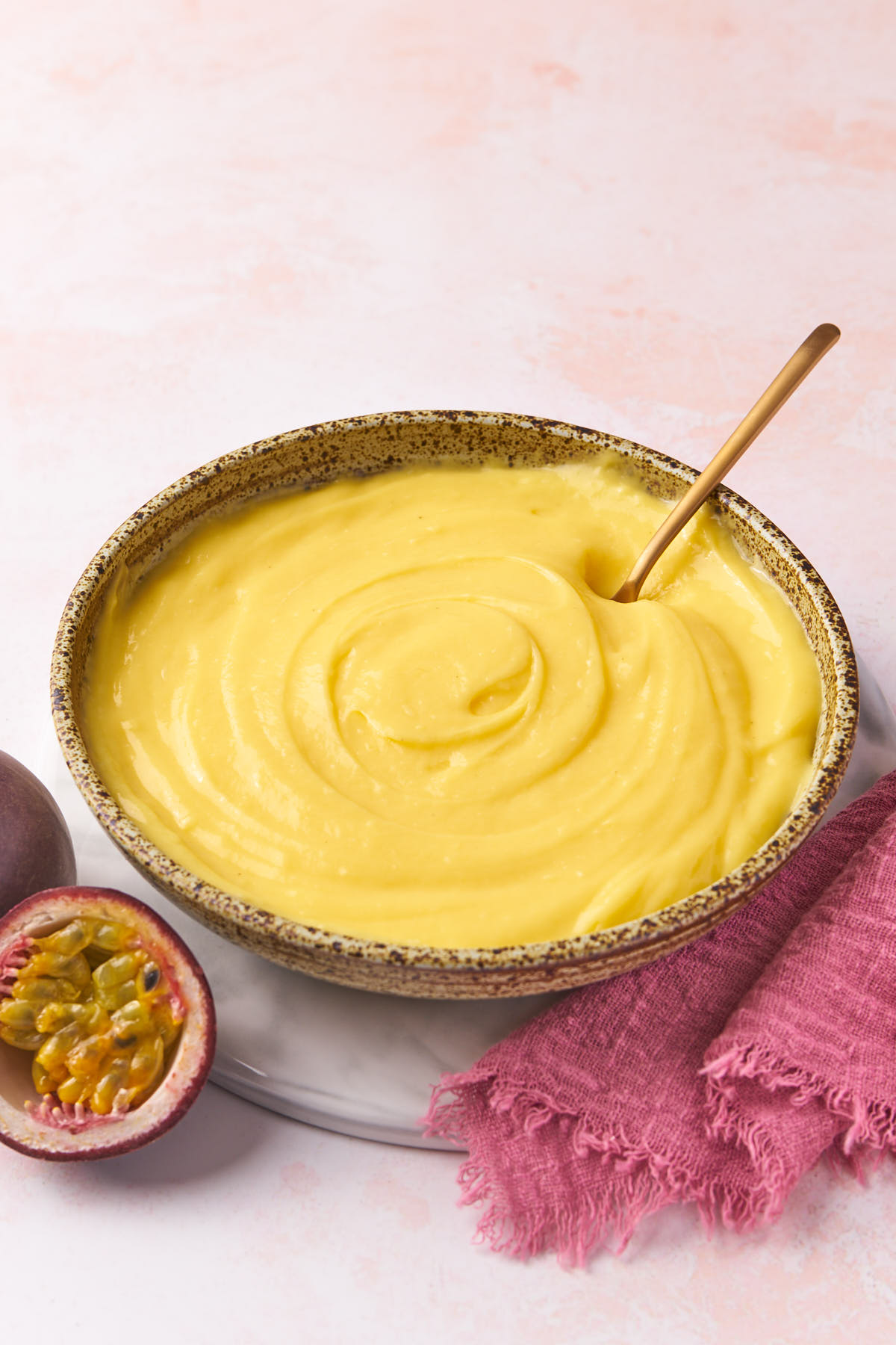 a bowl of passion fruit filling with sliced passion fruit alongside and a napkin.