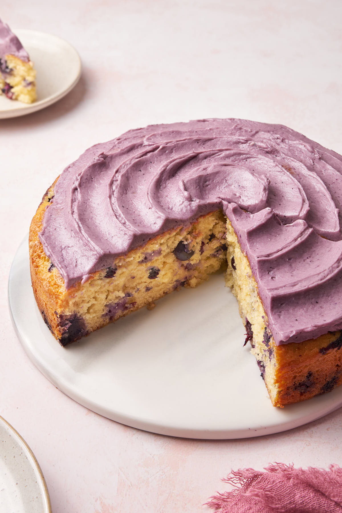 vanilla blueberry cake on a marble cake board.