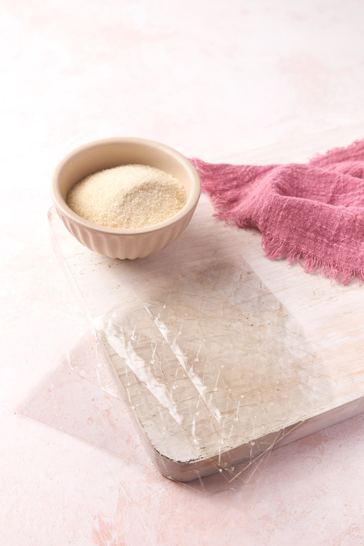 A bowl of gelatin powder alongside gelatin sheets.