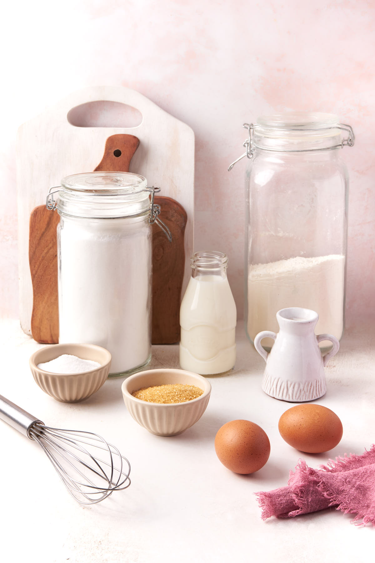Pantry baking ingredients, including flour, sugar, milk and eggs, arranged simply.