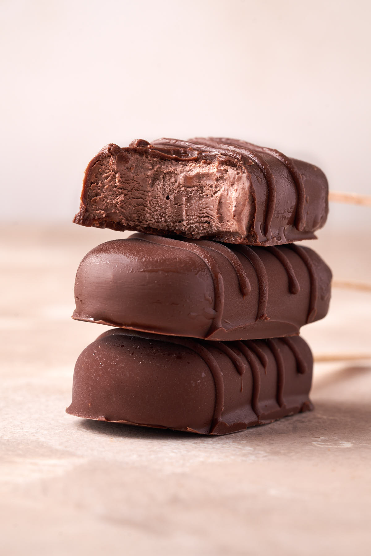 Three chocolate dipped ice cream bars: one has a bite taken out, showing the chocolate ice cream inside.
